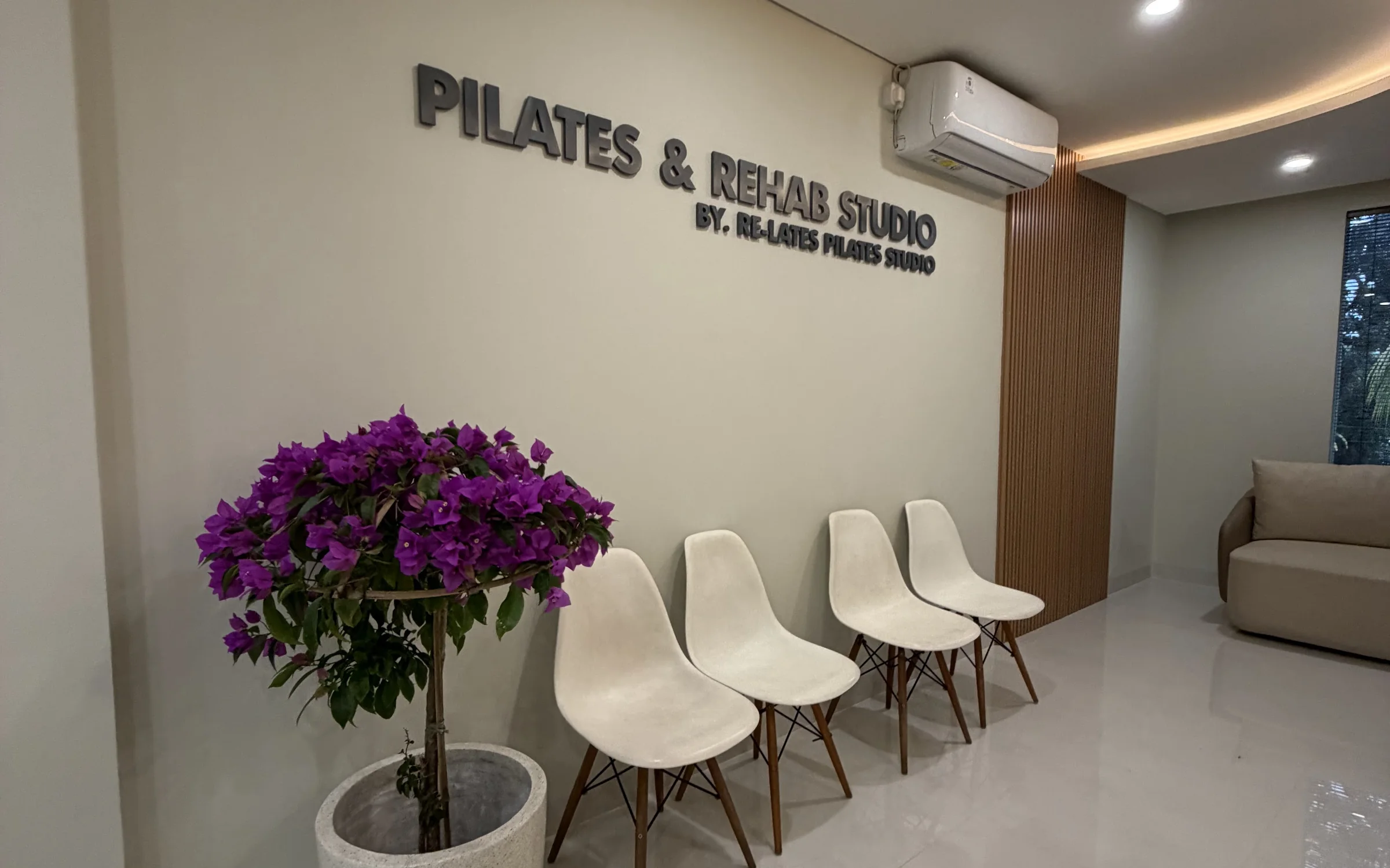 Reception: the Pilates & Rehab Studio sign, white chairs and bougainvillea