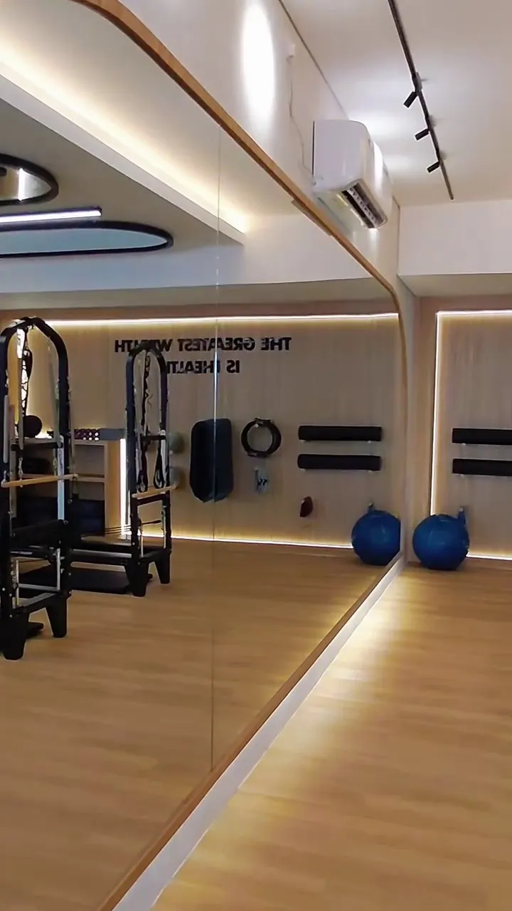 The studio's mirror wall and reformers along the oak floor